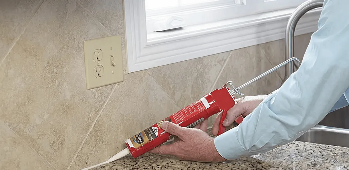 Handyman applying caulk along a kitchen backsplash and countertop seam in Saint Petersburg, FL