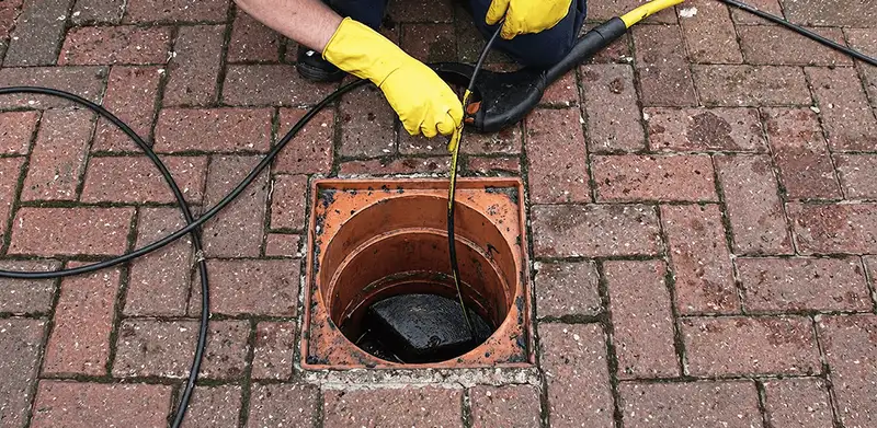 Drain cleaning technician using a drain snake to clear a clogged drain in Saint Petersburg, FL