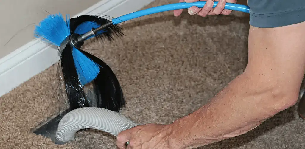 Dryer vent cleaning technician brushing lint from a vent line in Saint Petersburg, FL
