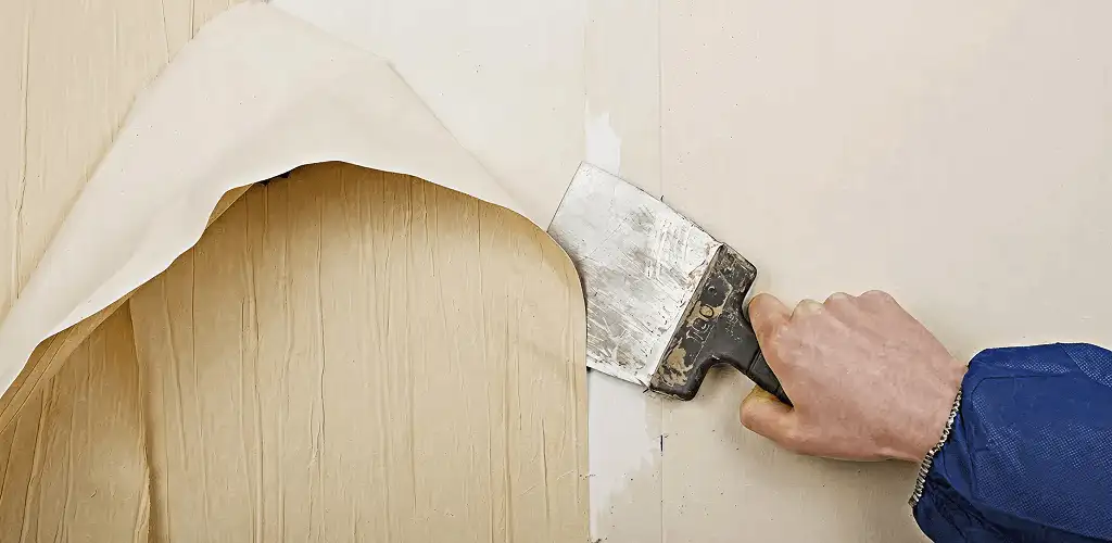 Handyman removing wallpaper with a scraper for wall preparation in Saint Petersburg, FL