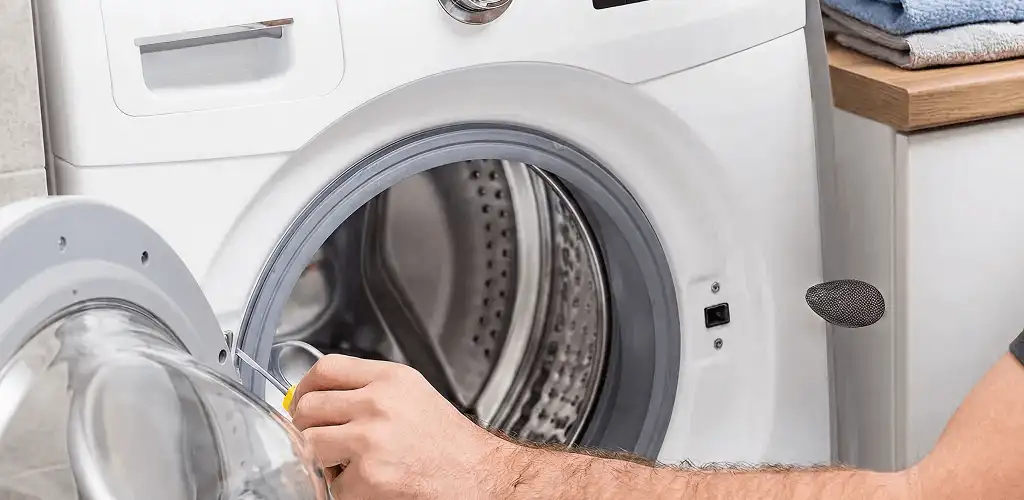 Handyman repairing a front-load washing machine and inspecting the drum in Saint Petersburg, FL