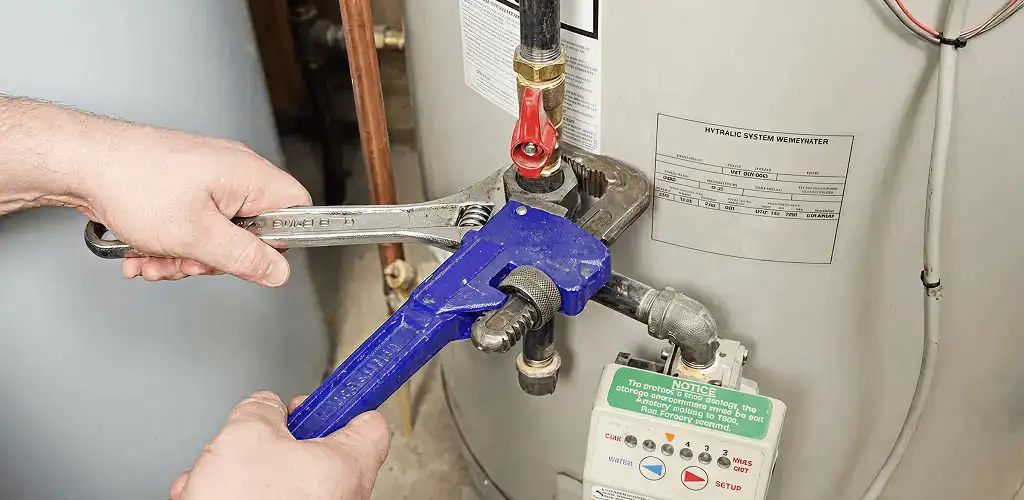 Water heater repair technician tightening the shutoff valve and supply line in Saint Petersburg, FL
